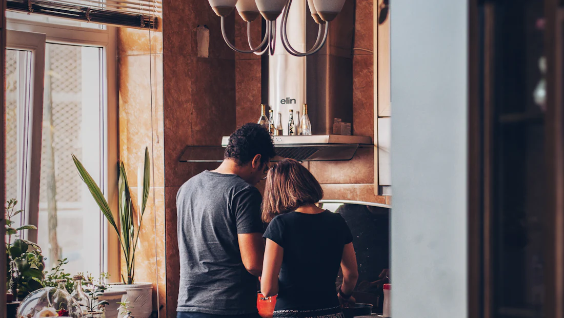 Two people cooking together in a warmly lit kitchen